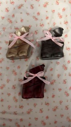 three pairs of shoes are tied up on a floral sheet with pink ribbon around them