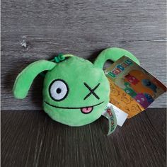 a green stuffed animal sitting on top of a wooden floor next to a package of candy