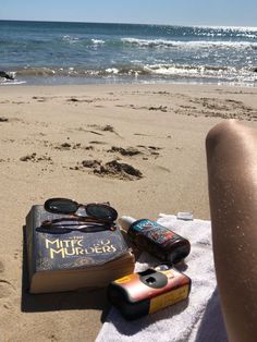 a book and some sunglasses on a towel at the beach