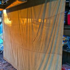 an outdoor kitchen covered in tarp next to a building with lots of junk on the ground