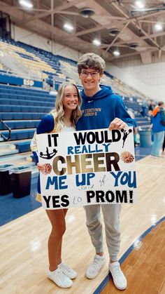 a man and woman holding a sign in front of a basketball court with the words cheer me up for you yes prom