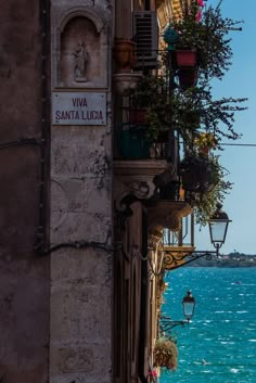 an old building with flowers hanging from it's balcony next to the ocean in venice, italy