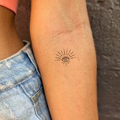 a woman's arm with a small sun tattoo on the left side of her arm