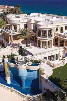 an aerial view of a mansion with a pool in the foreground and ocean in the background