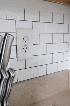 an electrical outlet on the wall next to a white tile backsplash in a kitchen