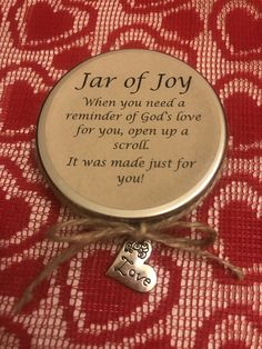 a glass jar with a poem on it sitting on a red tablecloth next to a small heart