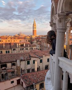 a woman standing on top of a balcony next to tall buildings