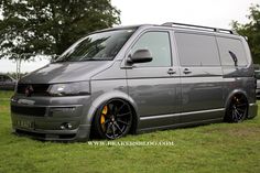 a grey van parked on top of a lush green field