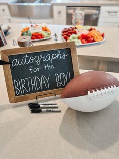 a football sitting on top of a counter next to a sign that says autographs for the birthday boy