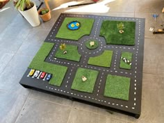 a play table made out of grass with cars and trucks on the road in it