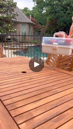 a woman sitting at a table with a cooler on it's back deck next to a pool