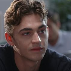 a close up of a person wearing an earring and looking at the camera with a serious look on his face