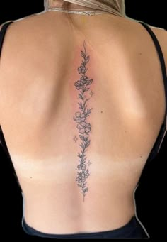 the back of a woman's neck with flowers on it and leaves in the middle