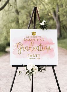 a welcome sign with flowers and greenery on it for a graduation party in the woods