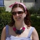 a woman wearing sunglasses and a pink headband is standing in front of some bushes