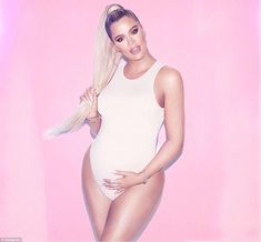 a woman in a white bodysuit with long blonde hair standing against a pink background