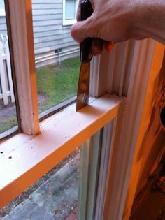 a person holding a bottle near a window sill with a knife in it's hand