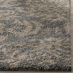 a gray and beige area rug on top of a wooden floor in a living room