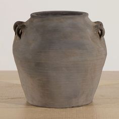 a gray vase sitting on top of a wooden table