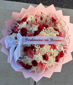 a bouquet of flowers is wrapped in pink and white paper with a ribbon that says perdosaname mi hemosa