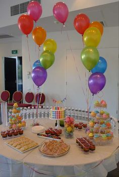 a table topped with lots of desserts and balloons