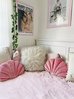 a bed with pink pillows and pictures on the wall above it, along with other decorative items