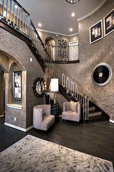 a living room filled with furniture and a stair case next to a wall mounted clock