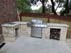 an outdoor bbq with grill and firewood stacked in it