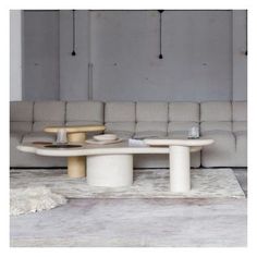 a white table sitting on top of a rug in front of a gray couches