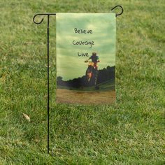 a sign that says believe courage live on it in the grass with a photo of a person riding a motorbike