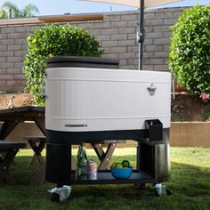 a cooler sitting on top of a wooden table in the grass next to a picnic table