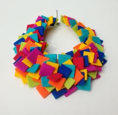 a multicolored necklace is displayed on a white surface