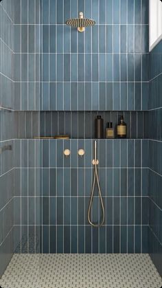 a bathroom with blue tiles and a shower head in the corner, along with two soap dispensers