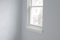 the corner of a room with a window and white paint on the walls is shown