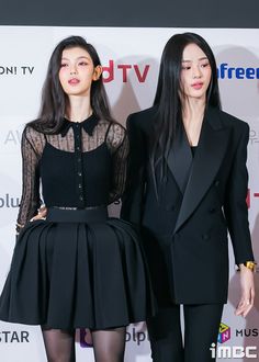 two women standing next to each other on a red carpet