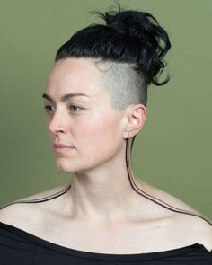 a woman with black hair is looking off to the side and has her head shaved