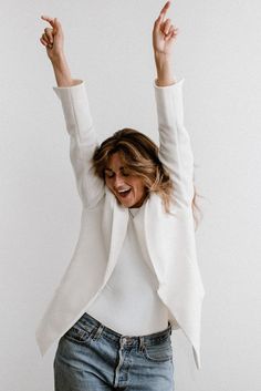 Photo of a woman in a white blazer and blue jeans smiling with her hands over her head. Personal Brand Photoshoot, Brand Photoshoot, Brand Photographer