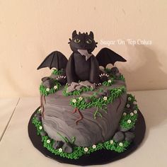 a birthday cake decorated with an image of a dragon sitting on top of a rock