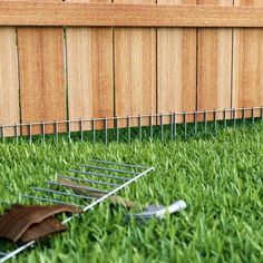 a lawn mower laying in the grass next to a fence and wooden slats