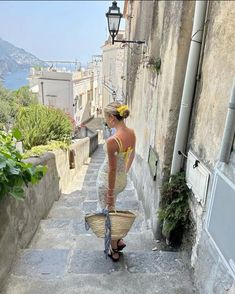 a woman is walking down the street with a basket in her hand and wearing a yellow top