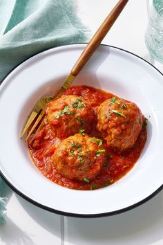 a white plate topped with meatballs covered in sauce and garnished with parsley