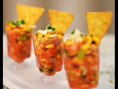 small cups filled with salsa and chips on a white tray, ready to be served