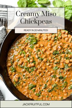 creamy miso chickpeas in a skillet with spinach leaves on the side