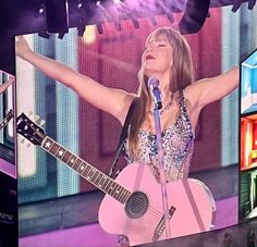 a woman singing into a microphone while holding a guitar