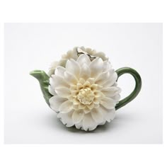 a white flower sitting on top of a green tea pot