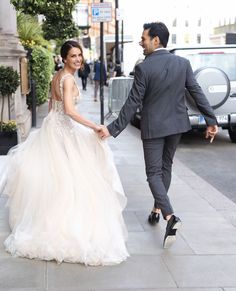 a bride and groom walking down the street holding hands