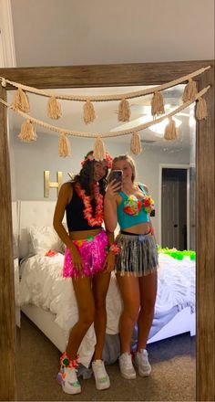 two women standing next to each other in front of a mirror with tassels hanging from it