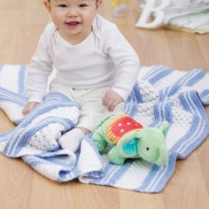 a baby sitting on the floor with a blanket