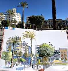 an open sketch book with palm trees and buildings in the background