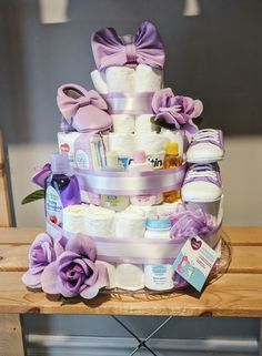 a large diaper cake with lots of items on the top and purple flowers around it